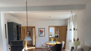 A modern living room with a sofa, armchair, coffee table, and dining area with chairs and a table. - Holiday house near Baltic Sea (Bay of Lübeck) (Ahrensbök)