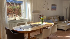 A dining area with a wooden table, chairs, and a vase of flowers. - Holiday house near Baltic Sea (Bay of Lübeck) (Ahrensbök)