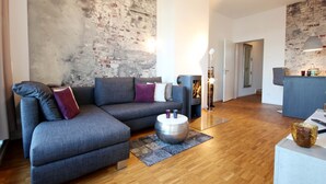Ein modernes Wohnzimmer mit einem grauen Ecksofa, einem runden Couchtisch und einem Kamin.