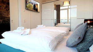Ein Hotelzimmer mit zwei Betten, einem großen Spiegel, einem Fernseher und Balkonblick.