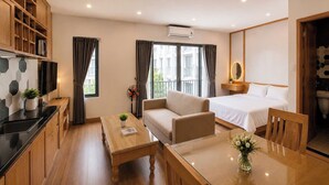 A modern hotel room with a kitchenette, a sofa, a bed, a dining table, and a bathroom. - Minh Hưng Apartment (Da Nang)