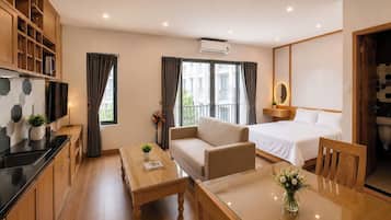 Quarto de hotel moderno com cozinha compacta, sofá, cama, mesa de jantar e banheiro.