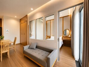 A modern hotel room with a sofa, a dining table, and a mirror.