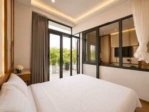 A hotel room with a large bed, a sliding glass door to a balcony, a flat-screen TV, and a large mirror.