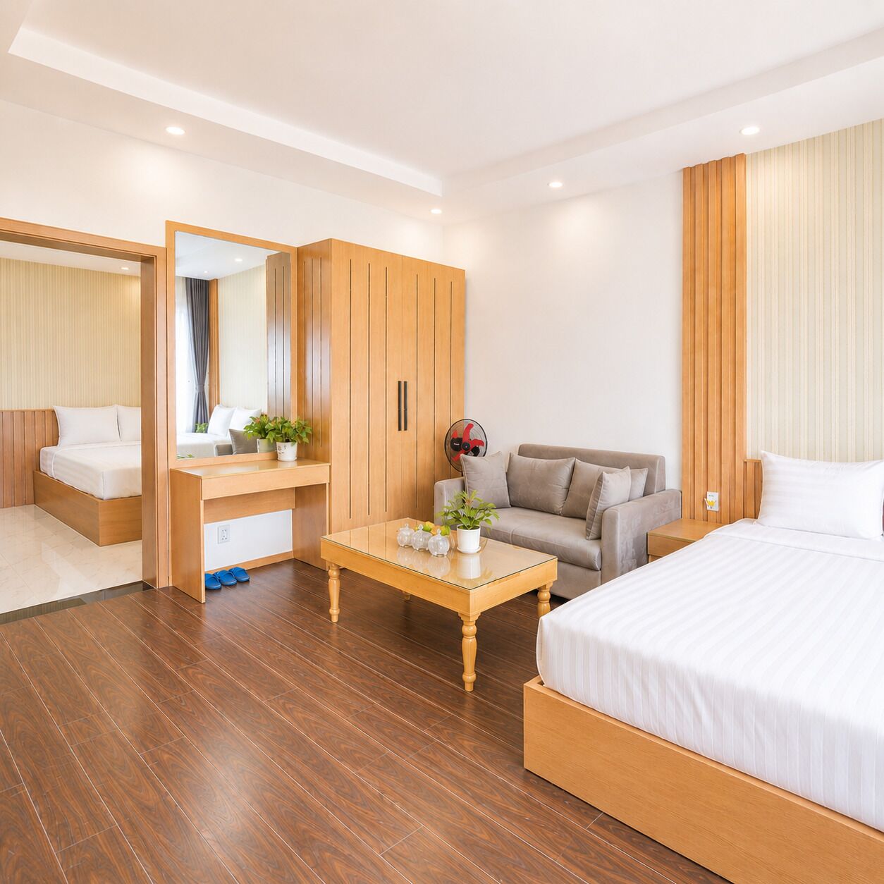Ett hotellrum med en säng, ett skrivbord, en soffa, en spegel och en garderob.