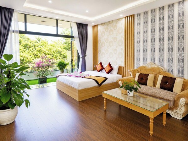 Habitación de hotel con cama, sofá y vistas a zonas verdes.
