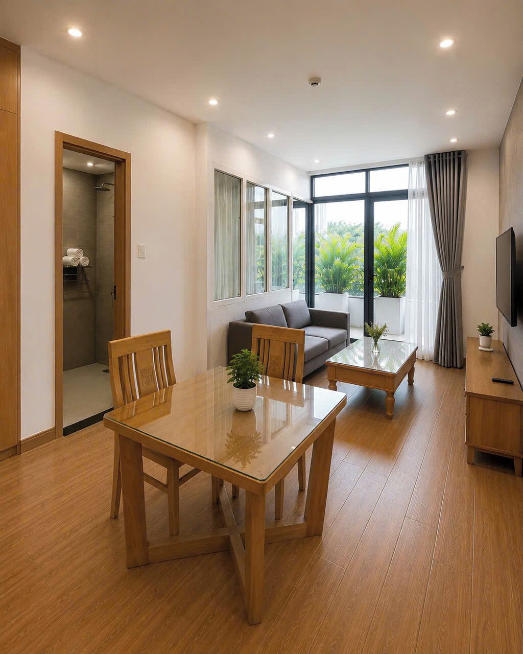 A modern living room with a wooden dining table, sofa, and a TV on a wooden stand.