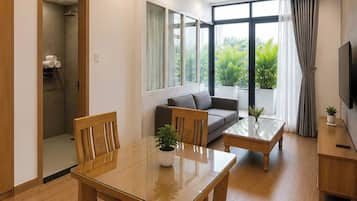 Uma sala de estar moderna com uma mesa de jantar de madeira, sofá e televisão sobre um suporte de madeira.