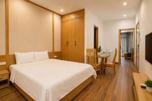 Habitación de hotel con cama, armario de madera, escritorio con silla, televisor y planta en maceta.