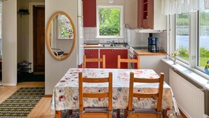 Une cuisine compacte avec un coin repas, un grand miroir et une fenêtre donnant sur un espace verdoyant.