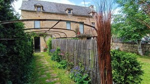 Ein Steinhaus mit Garten und Holzzaun.