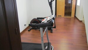 A room with a treadmill, a stationary bike, and a door leading to another room. - Bed and breakfast SPA - Residence Requirement -2 People -Breakfast included (Saint-Brevin-les-Pins)