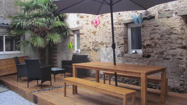 An outdoor patio with wooden furniture, a table, and an umbrella. - Bed and breakfast SPA - Residence Requirement -2 People -Breakfast included (Saint-Brevin-les-Pins)
