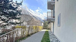 A narrow pathway leading to a building with a mountain view, a balcony, and a stone border. - Chamonix center, 64m², 6 pers., 2 bedr., parking (Chamonix-Mont-Blanc)