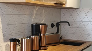 A kitchen with a wooden countertop, a sink, and stainless steel appliances including a kettle, a coffee maker, and a toaster. - Modern flat facing south with view over mountains and lake (Murnau)