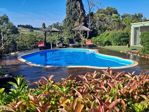 Una piscina con cubierta de madera, rodeada de exuberante vegetación y árboles.