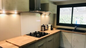 A modern kitchen with a gas stove, a coffee maker, and a window overlooking greenery.
