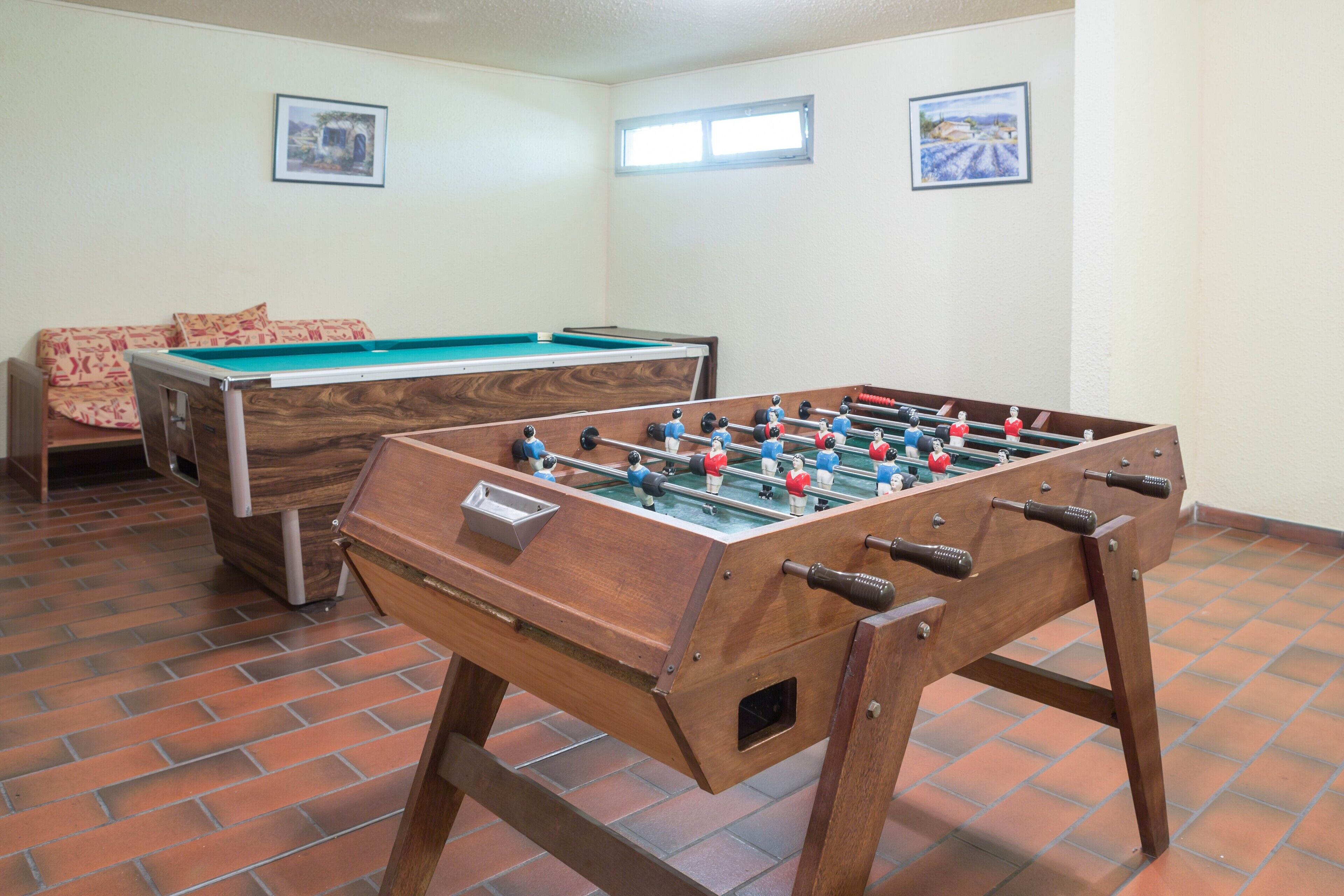 Une pièce équipée d’un baby-foot, d’une table de billard et d’un canapé.
