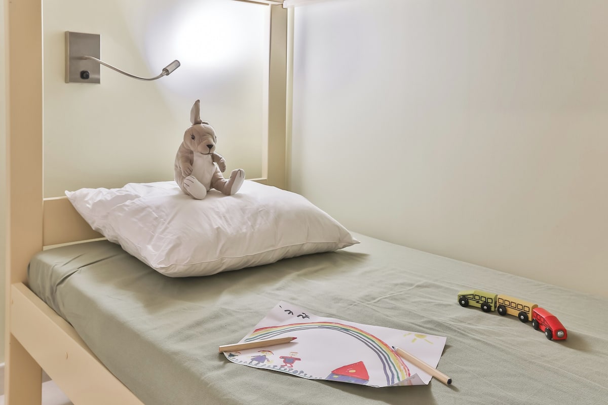Un lit avec un oreiller, un jouet en peluche et un train jouet posés sur le lit.