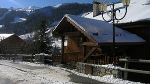 Eine Holzhütte mit schneebedecktem Dach, einer Steinmauer und einer Straßenlaterne.