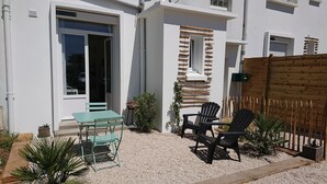A patio area with a table and chairs, a wooden fence, and a small garden. - Our islands : Ile du Pilier - 200m Beach (Saint-Jean-de-Monts)