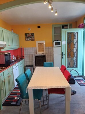 Une cuisine compacte avec un coin repas, comprenant un crédence carrelée, un four à micro-ondes et une petite table à manger avec des chaises.