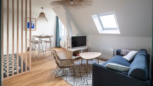A modern loft apartment with a dining area, a sofa, and a TV.