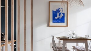 A dining area with a table set for four, white chairs, and a framed map on the wall.