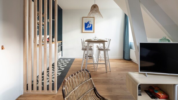 A modern living room with a dining area, a TV, and a staircase.