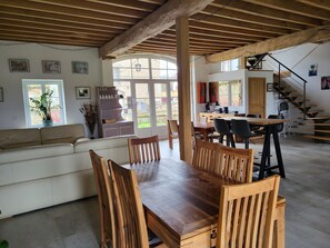 A spacious dining area with a wooden table and chairs, a sofa, and a staircase leading to an upper level. - Large luxury gite 160 m2, capacity 6 adults + 3 children with spa (Montillot)