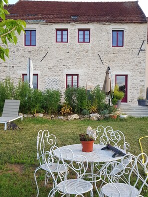 Set amidst a serene garden, this charming residence offers a tranquil outdoor space with a table and chairs.