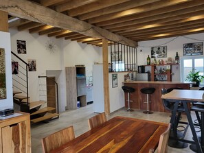 A modern kitchen with wooden beams, a bar area with stools, and a dining table with chairs. - Large luxury gite 160 m2, capacity 6 adults + 3 children with spa (Montillot)