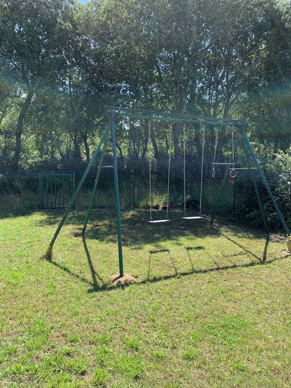 A swing set in a grassy area with trees in the background.