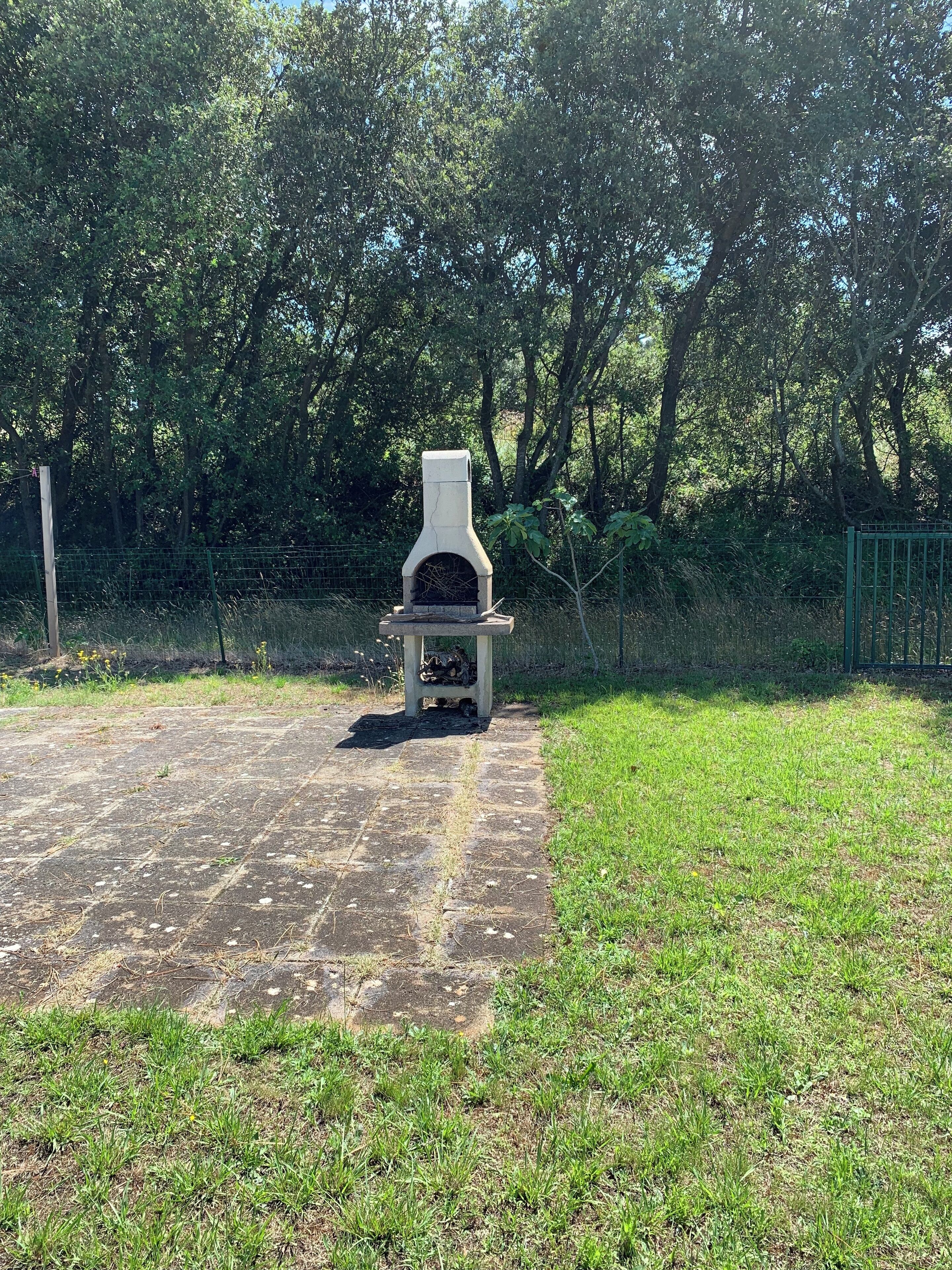 An outdoor barbecue grill in a grassy area with a paved path leading to it.