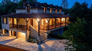 Une maison à deux étages dotée d’un balcon, de fondations en pierre et de nombreuses fenêtres.