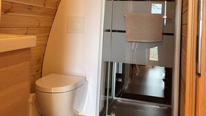Ett litet badrum med en duschkabin i glas, en toalett och en handduk som hänger på duschdörren.