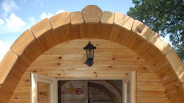 An arched wooden structure with a table set for two, a bottle, and glasses. - Our Pods at L'Adret, Rians en Provence (RIANS)