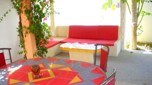 A round table with a colorful geometric pattern, surrounded by red chairs. - Villa pirogue: The huts of Saly (M bour)