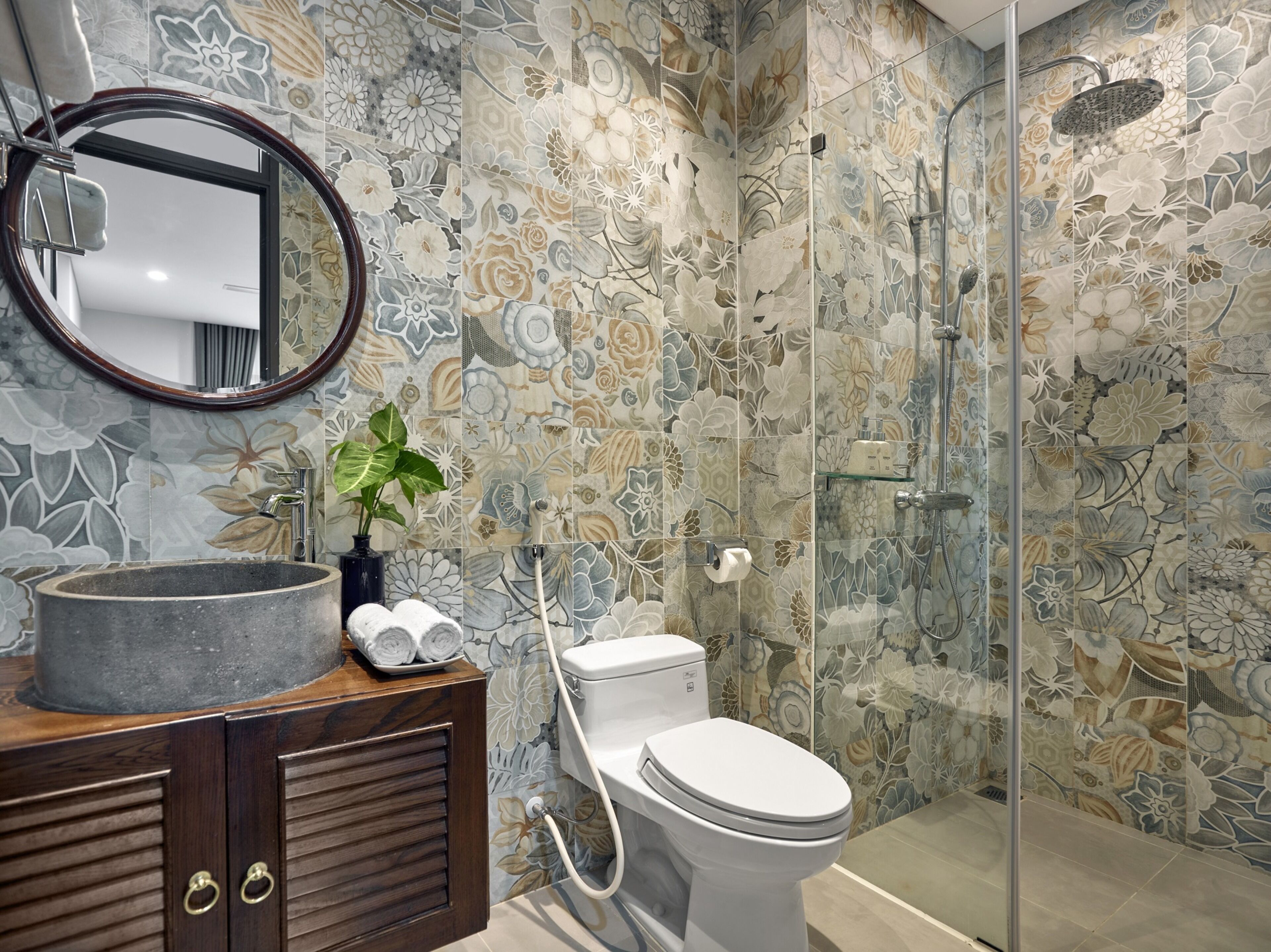 A bathroom with a round sink, a toilet, a shower with a glass door, and a mirror.