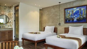 Une chambre d’hôtel avec deux lits, un banc en bois, un miroir, un tableau et un vase avec des fleurs.