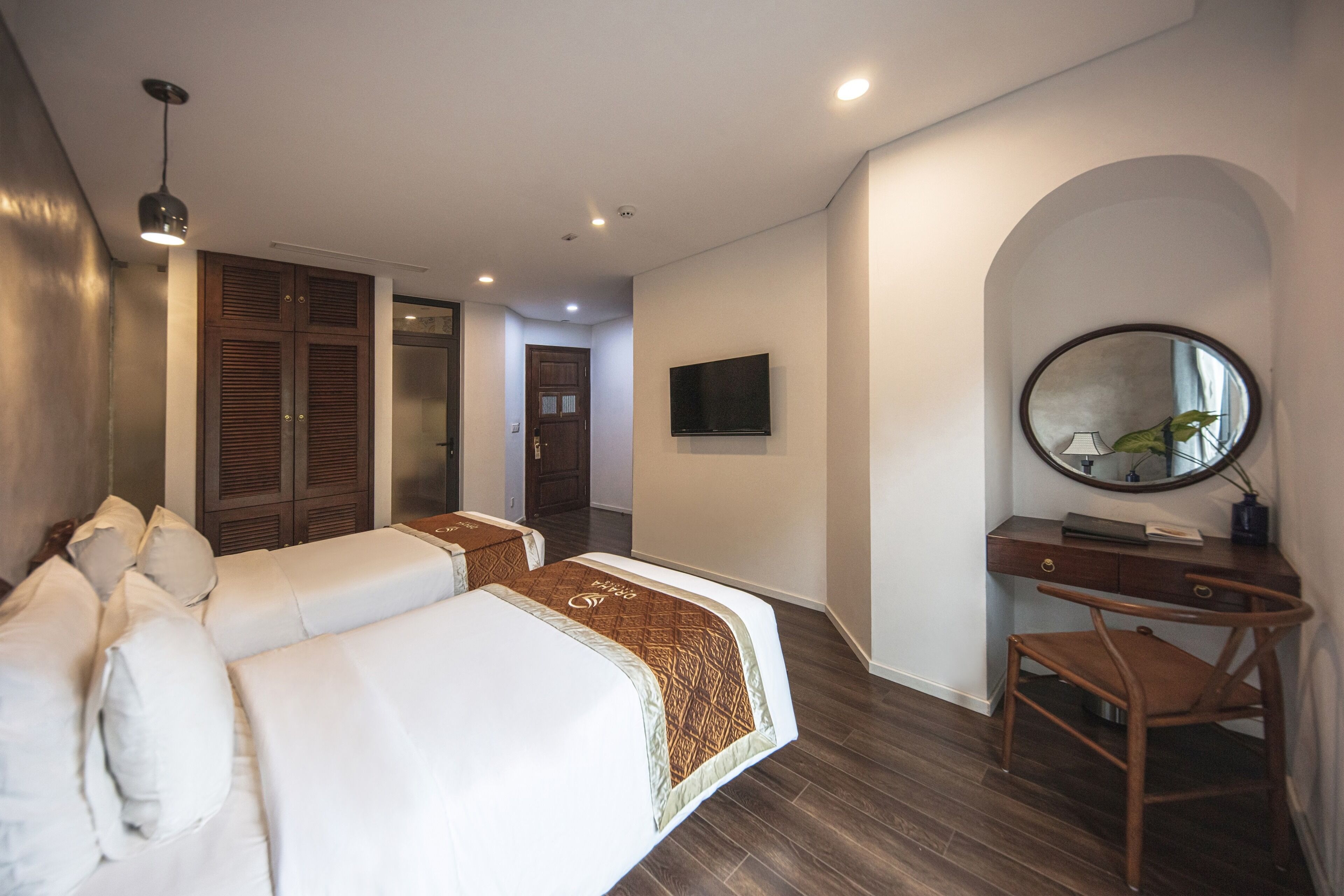 A hotel room with a large bed, a desk with a chair, a television, and a mirror.