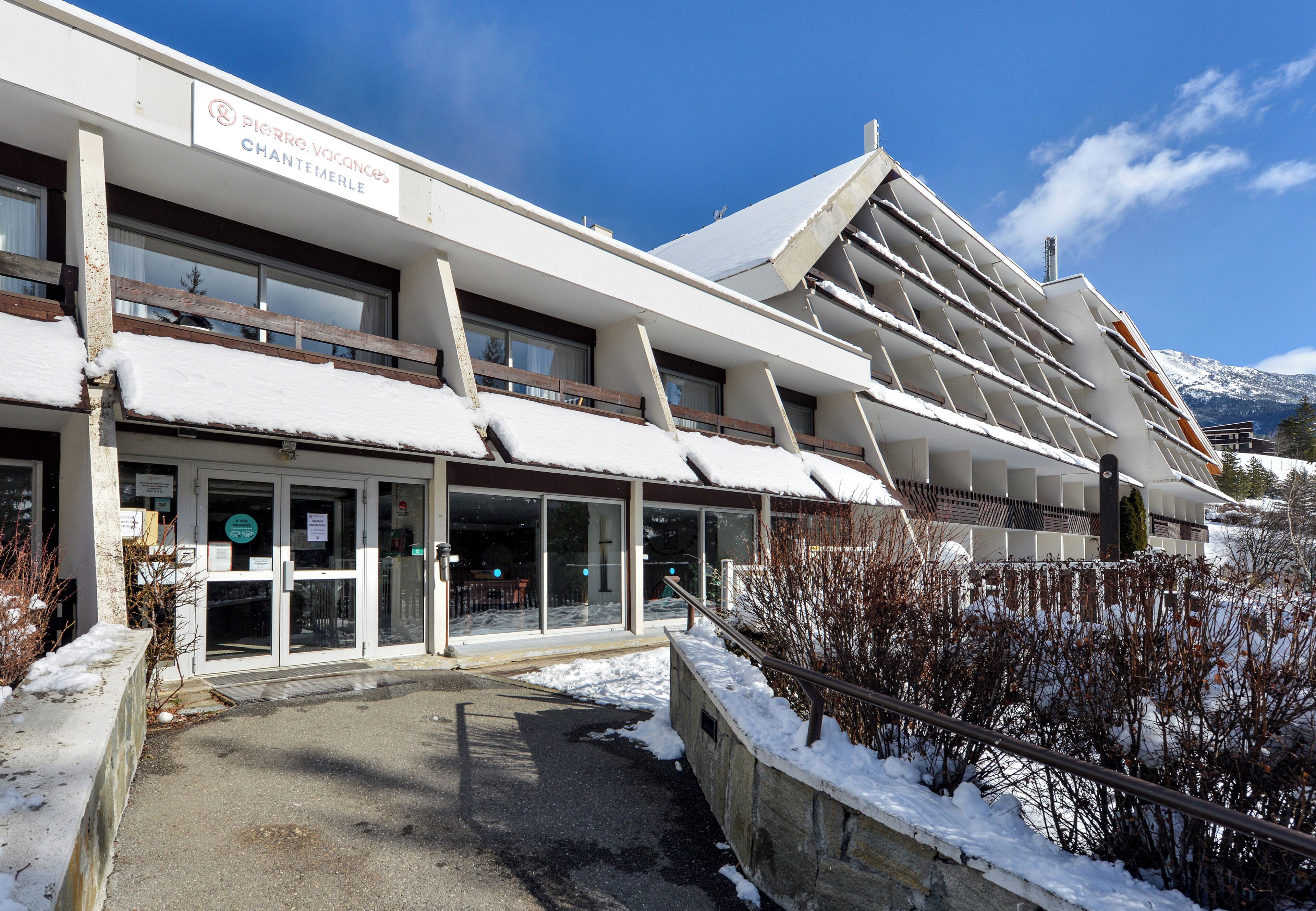 A hotel with a modern architectural design, featuring multiple balconies and a snow-covered roof.