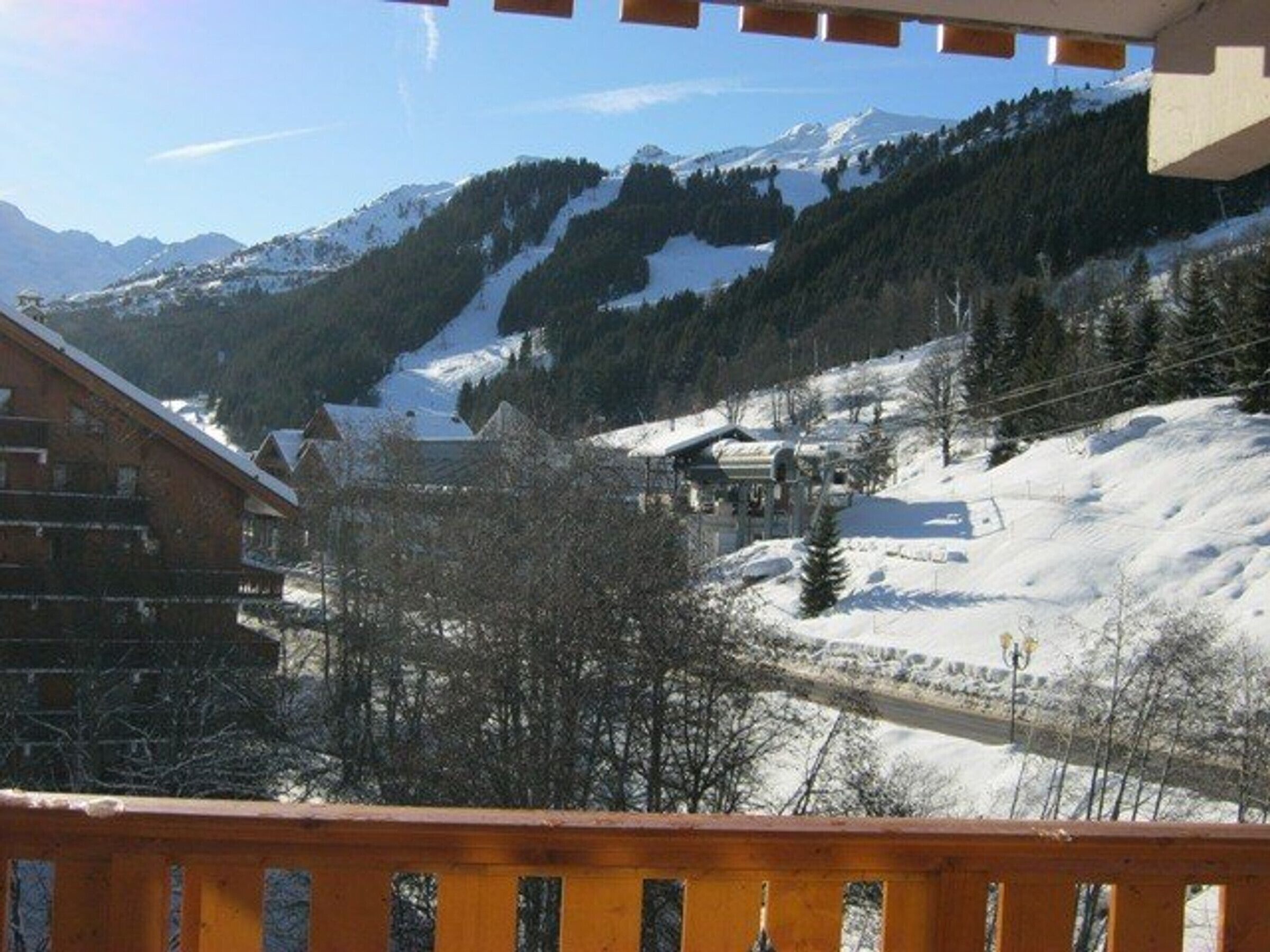 A snow-covered mountain landscape with a wooden building and a clear sky.