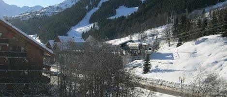 A snow-covered mountain landscape with a wooden building and a clear sky.
