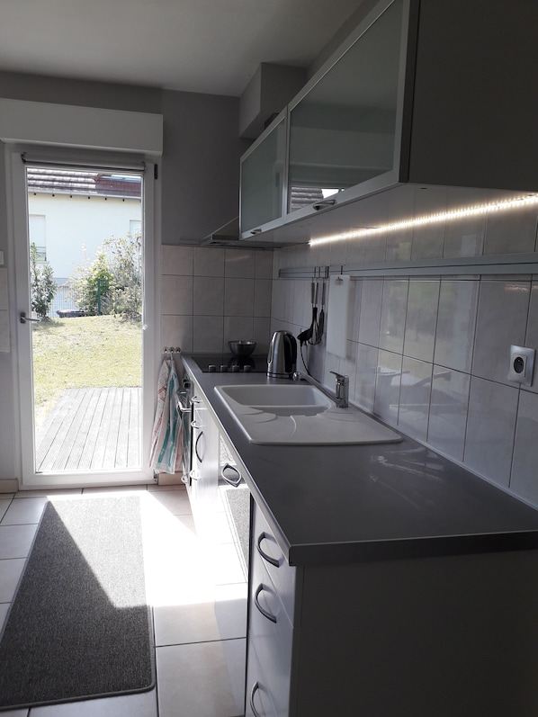 A modern kitchen with white cabinets, a double sink, and a stainless steel kettle.