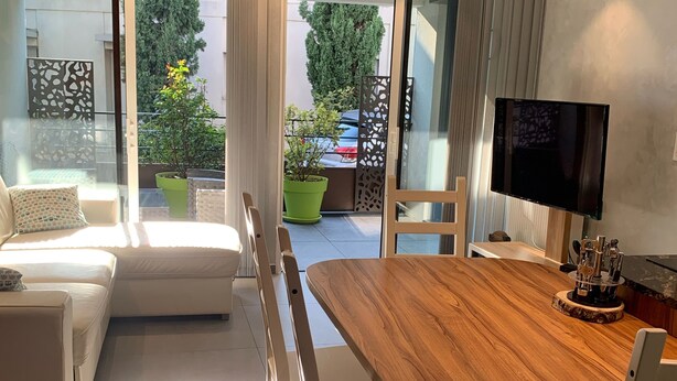 A modern living room with a wooden dining table, white chairs, a sofa, and a TV. - Apartment, Le Saint Simon rated 3 stars (Aix-les-Bains)