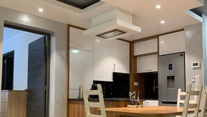 A modern kitchen with a central island, white cabinetry, and a built-in refrigerator. - Apartment, Le Saint Simon rated 3 stars (Aix-les-Bains)