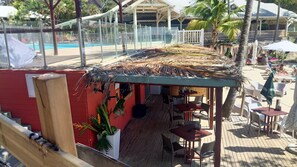 Enjoy a meal with a view of the pool area from our beachside restaurant, featuring outdoor seating and a bar.