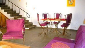 Een eethoek met een houten tafel en stoelen, een trap en een paarse bank.