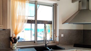 A modern kitchen with a large window, a stainless steel sink, and wooden cabinets.